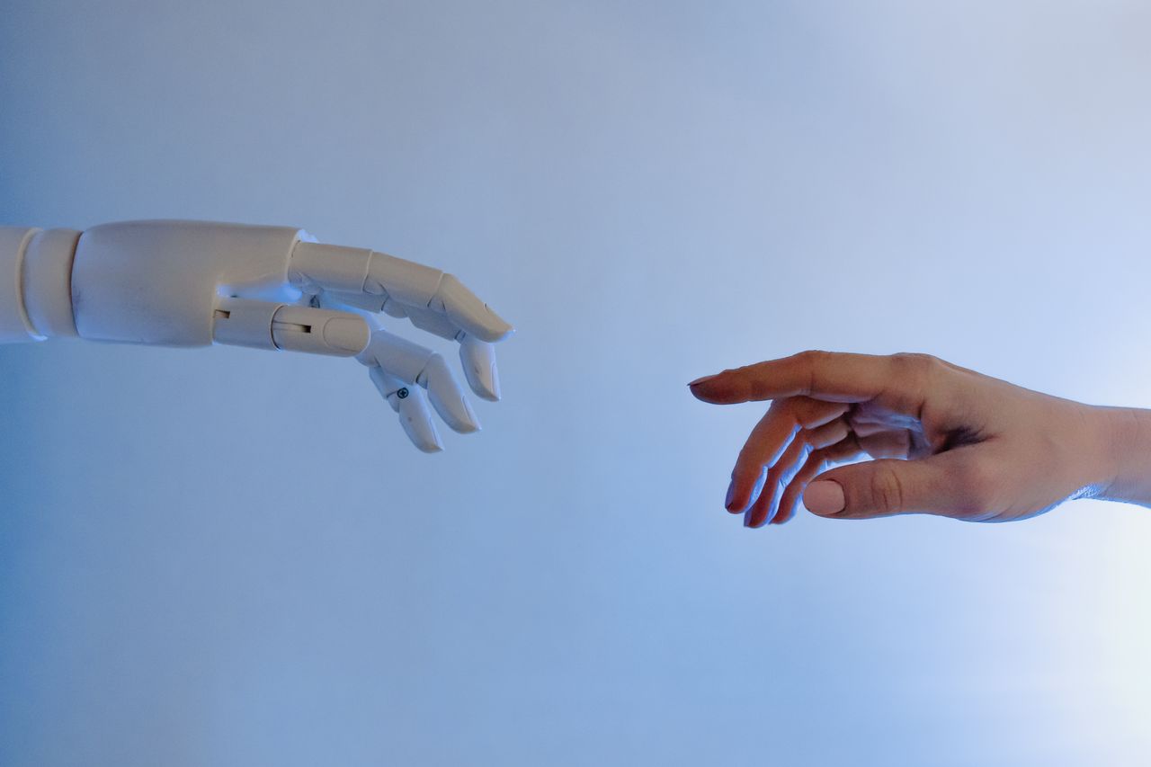 portfolio-img-01 A human hand reaching towards a robotic hand symbolizing technology and connection.